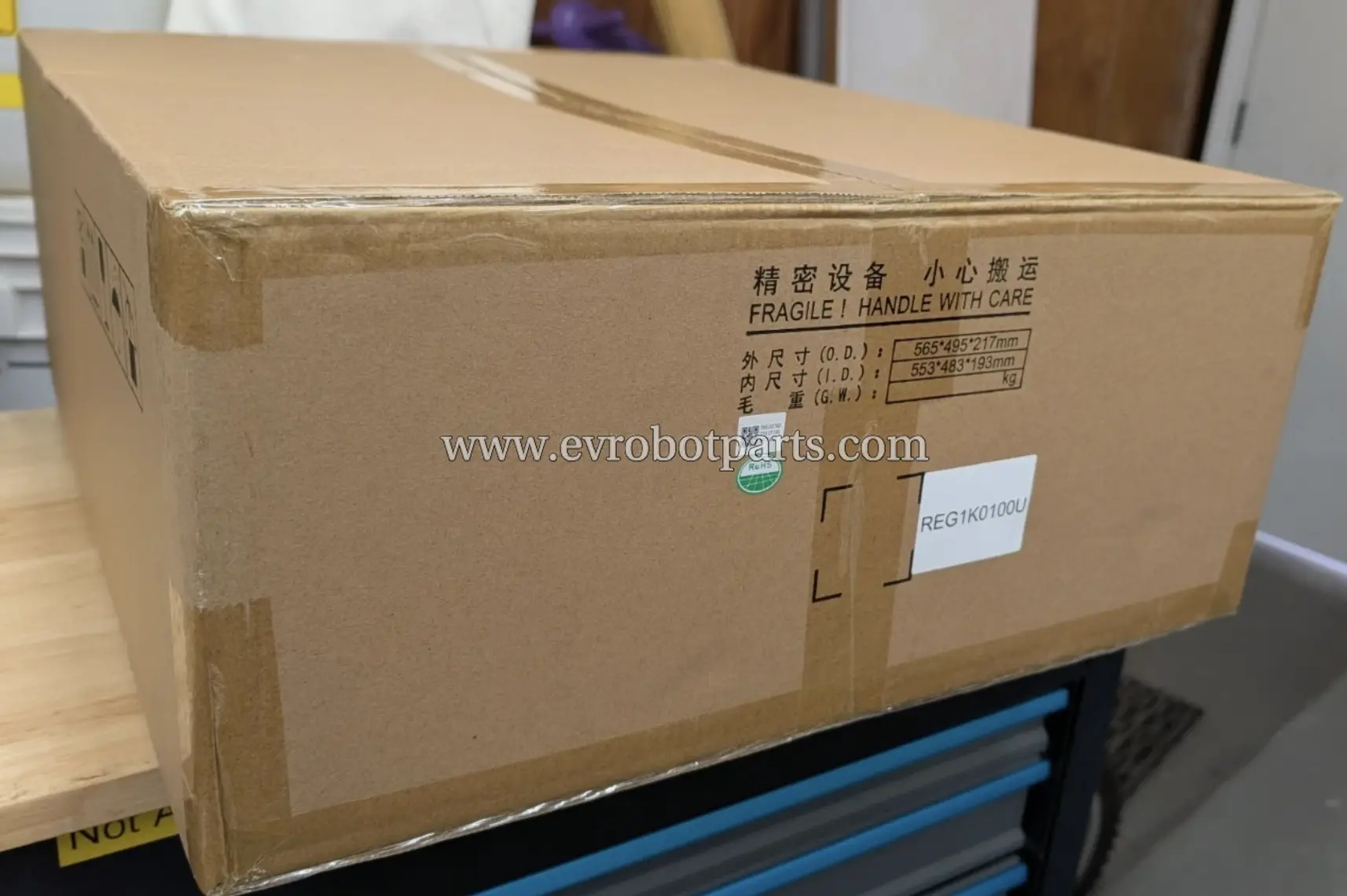 Cardboard shipping box for the Infy Power REG1K0100U power supply unit, with “FRAGILE | HANDLE WITH CARE” and outer dimensions printed on it.