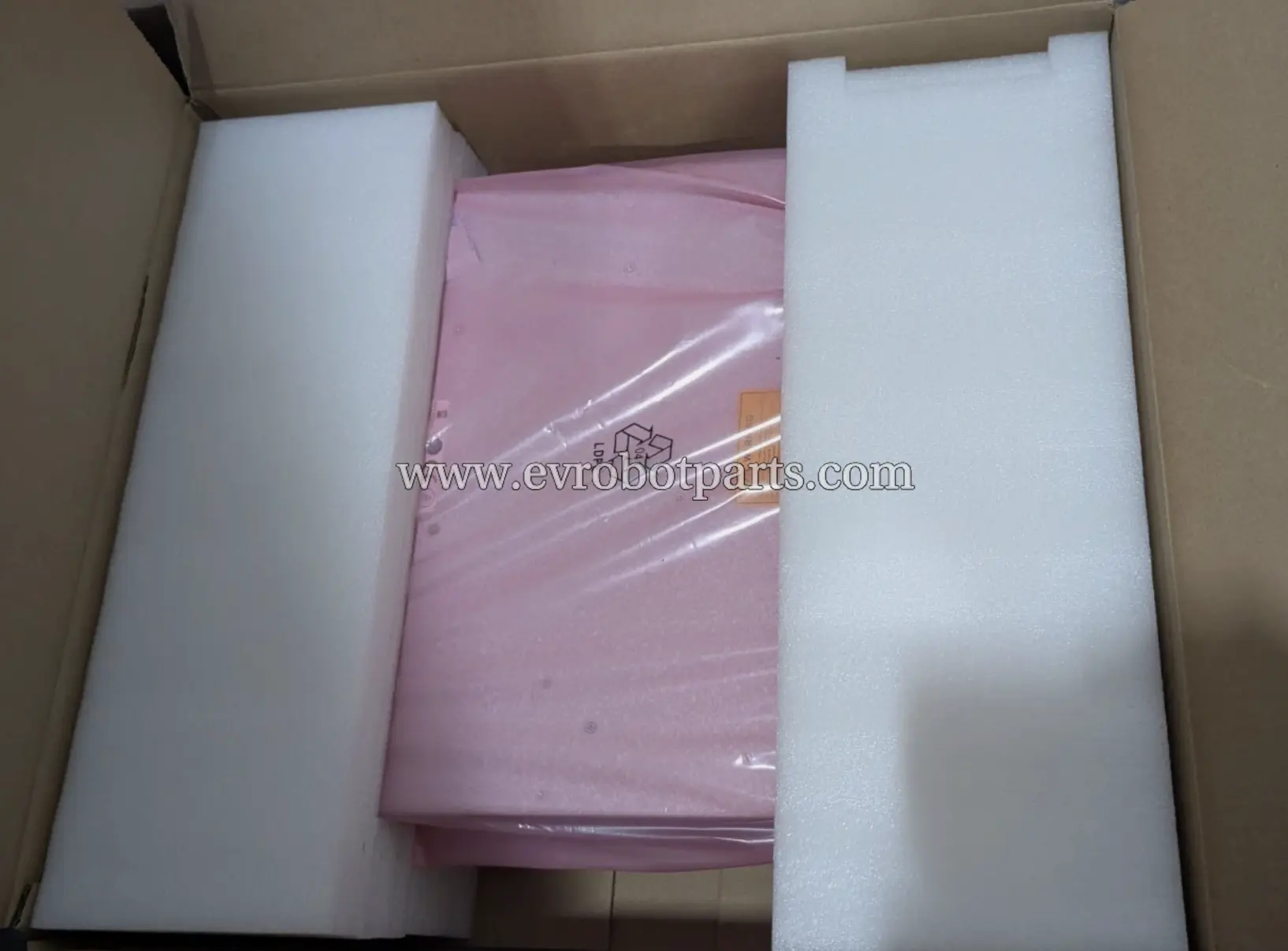 Inside view of the shipping box, showing the pink-wrapped power supply unit protected by white foam inserts.